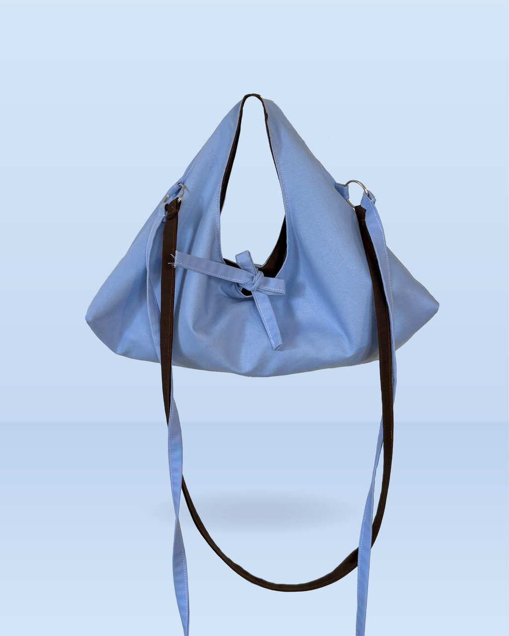 sac hobo bleu ciel et marron avec deux anses, une grande un petite et noeud pour fermer le sac.