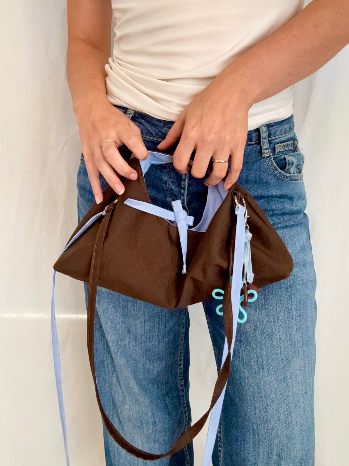 sac hobo reversible marron chocolat et bleu ciel face marron porté à la main par une femme en débardeur blanc et jean