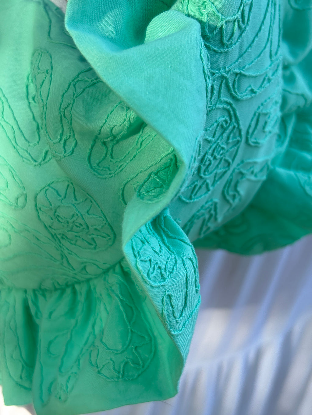 Zoom sur les détails de couture du sac cousu main Lagon de la marque sSIOU. Coloris turquoise lumineux aux broderies organiques en forme de fleurs.