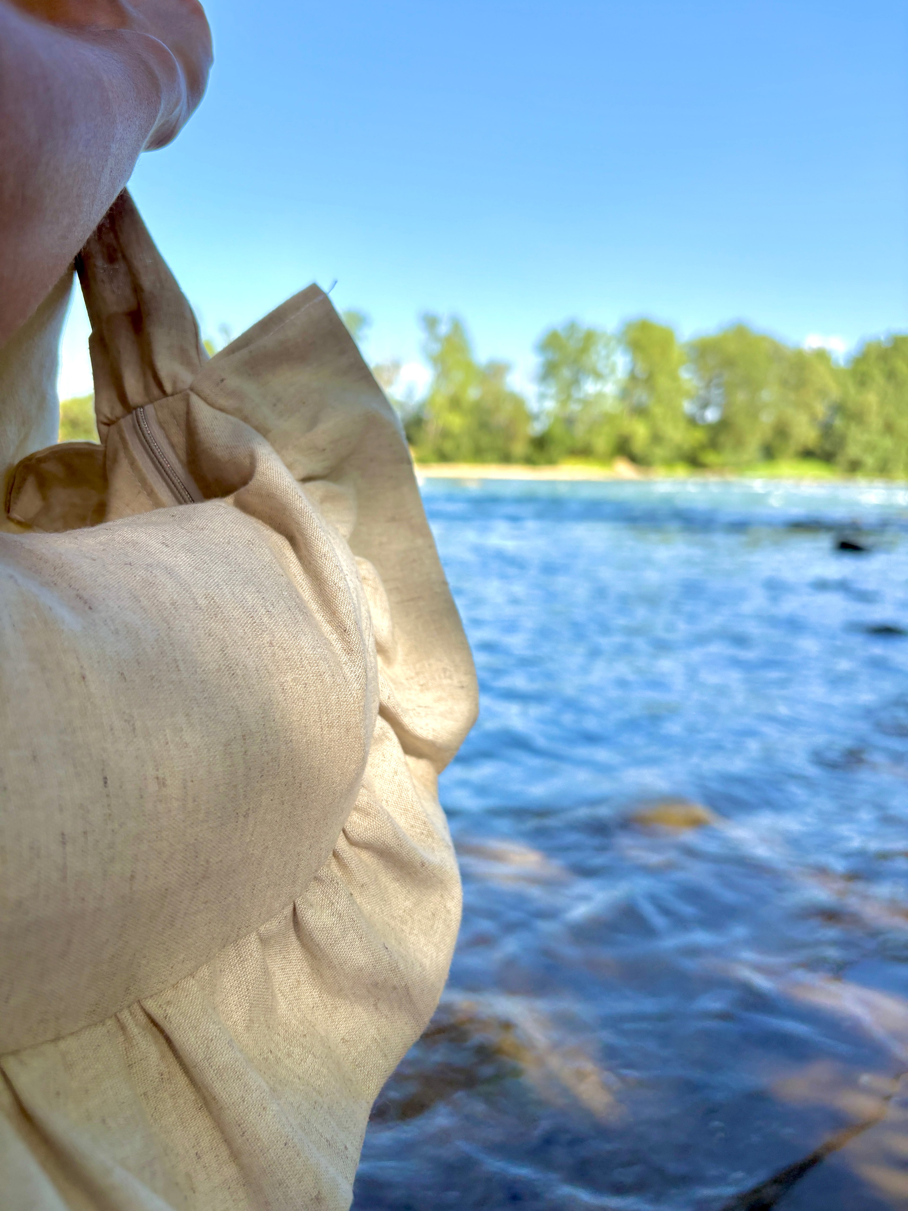 Zoom sur les détails de coutures du sac Sable de la marque SIOU, un coloris couleur beige lin avec un arrière plan de plage au bord de la mer.